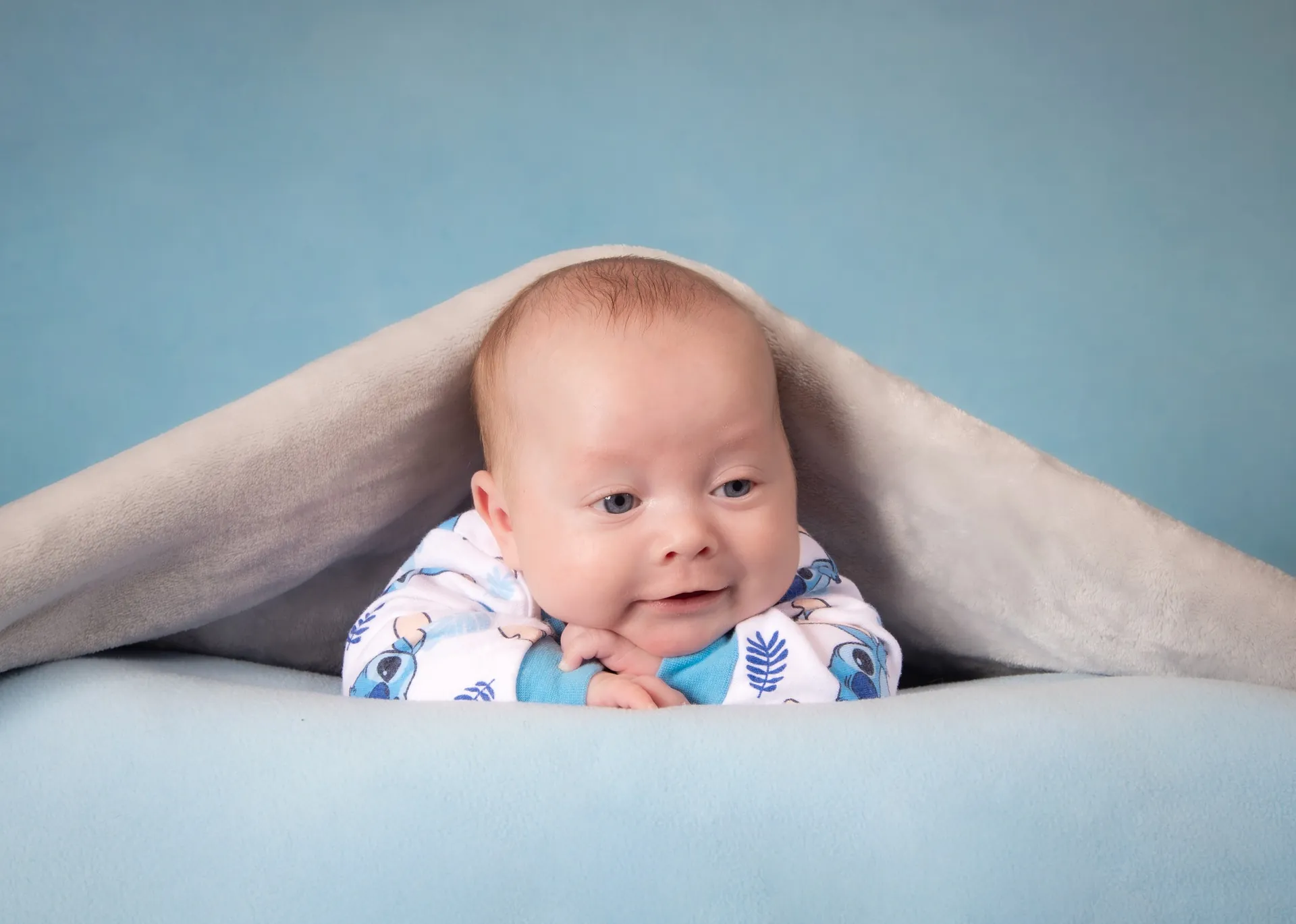 Newborn resting under a soft blanket — lifestyle studio portrait in Edmonton