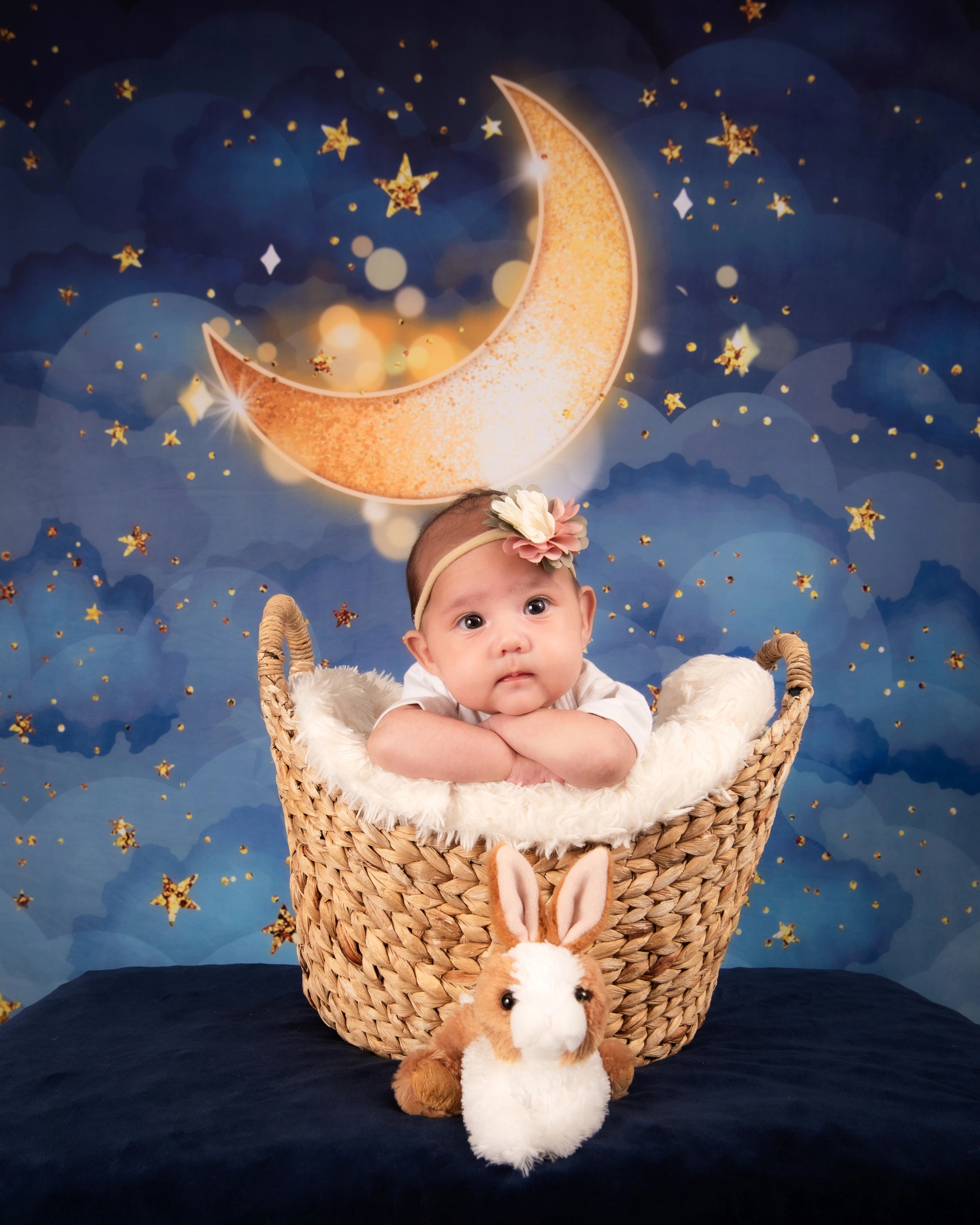 Baby in basket under crescent moon and stars backdrop — whimsical Edmonton milestone studio photo