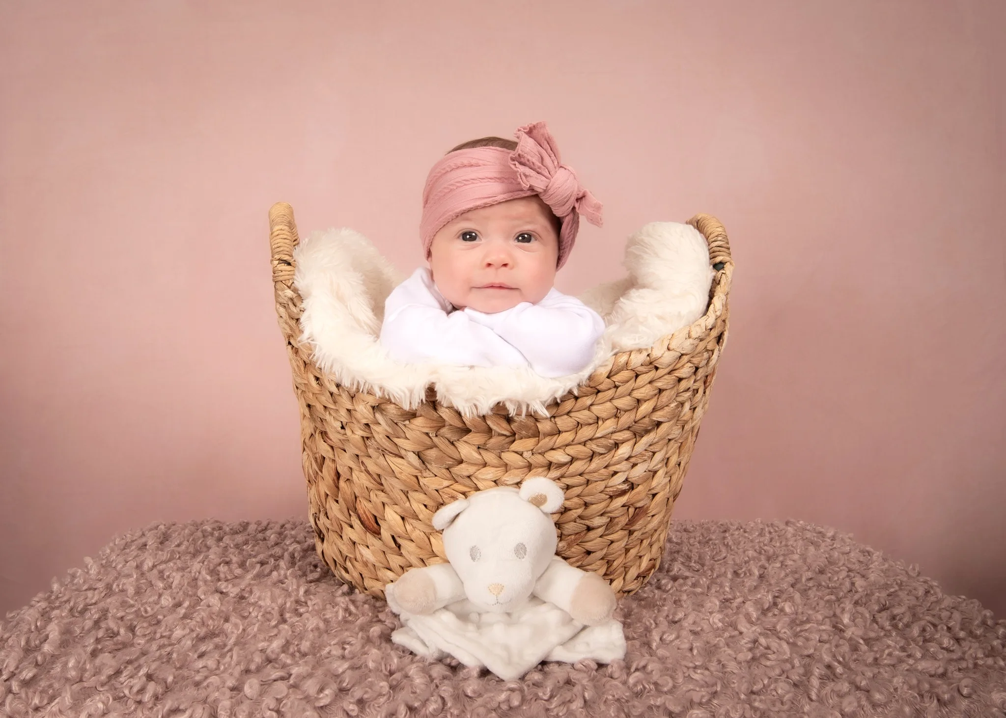 Newborn baby in a woven basket with soft blankets during studio session in Edmonton